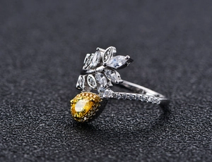 Macro shot of silver ring featuring leaf designs with yellow pear-cut and white marquise gems