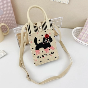 Detail of knitted cream crossbody bag featuring black cat embroidery and texture