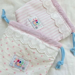 Detail of cute cotton drawstring bags with lace edges and colorful woven labels