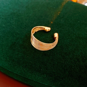 Nahaufnahme einer goldenen mehrlagigen Earcuff-Manschette auf grünem Samtstoff