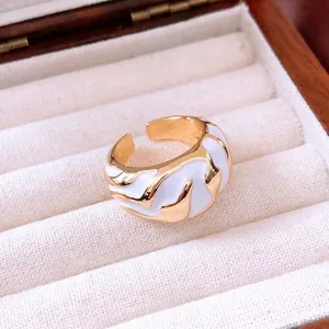 Irregular textured open ring with gold finish and white enamel wavy details