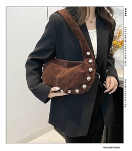 Dettaglio della borsa a spalla in camoscio marrone con borchie sferiche argentate e forma