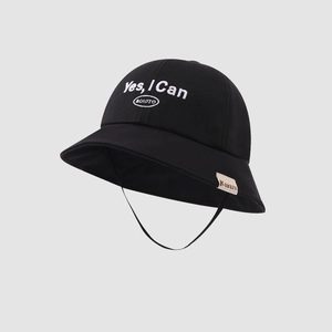 Close-up of black bucket hat featuring white embroidery and a side woven label