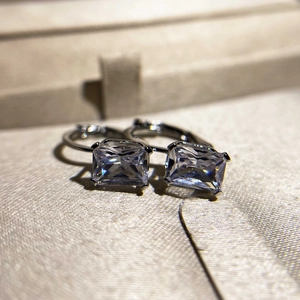 Dettaglio macro di orecchini a cerchio in argento con diamanti moissanite taglio smeraldo