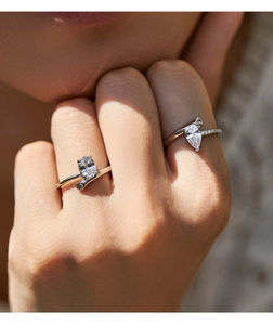 Close-up of pear and oval cut sparkling diamond rings on a model hand with silver bands
