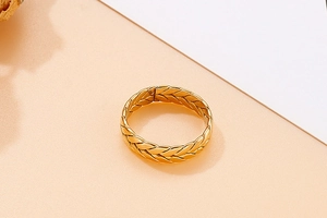 Dettaglio ravvicinato di un anello dorato con trama intrecciata e finitura metallica