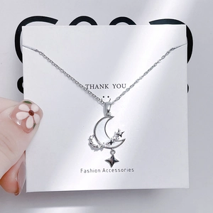 Close-up of silver moon and star pendant necklace with cubic zirconia inlay details