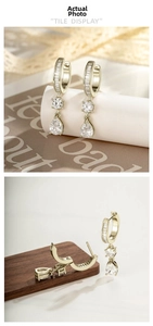 Detail of luxury teardrop zircon earrings in gold finish featuring rectangular cut stones