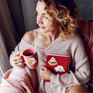 Close-up of waterproof reading stickers on a pink mug and notebook in a cozy setting