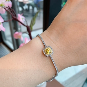 Detailed view of silver-tone bracelet with square yellow gemstone and halo diamonds