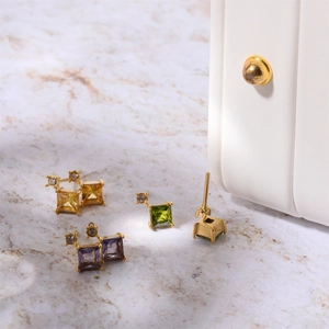 Detailed macro view of gold-plated square zircon stud earrings on marble background