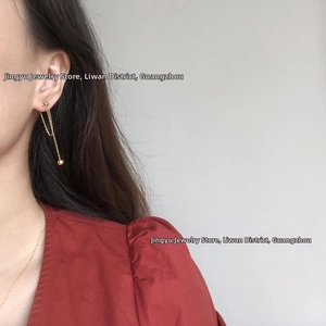 Detail of gold tassel chain earrings with small beads on a model for actual wear effect