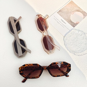 Flat lay of small geometric sunglasses in leopard print, beige, and transparent brown tones