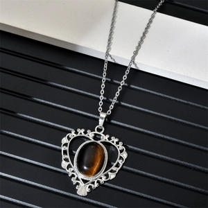 Macro detail of silver heart necklace with oval tiger eye stone and retro textures