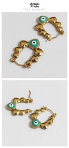Close-up of gold hoop earrings with heart links and turquoise evil eye charms