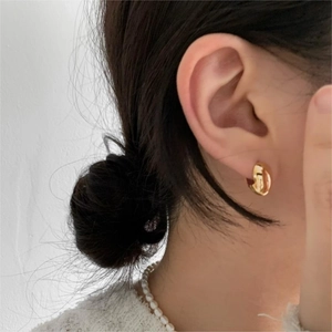 Close-up of model wearing gold-plated oval sterling silver hoop earrings with a sleek finish