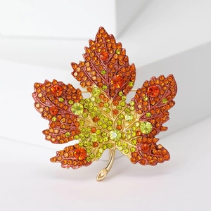 Sparkling maple leaf brooch with orange gradient rhinestones on white background
