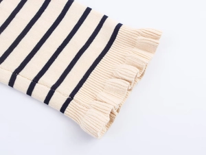 Détail des poignets à rayures d'un cardigan en maille avec bords volantés et texture côtelée