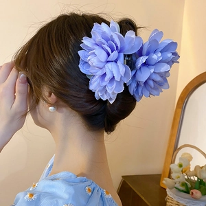 Elegant light blue fabric lotus hair claw clip worn by a model for a graceful hairstyle