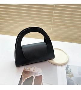 Detail of black lychee texture faux leather handbag with curved handle and flap closure