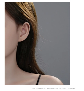Detail view of mirror finish silver earrings on female model with minimalist style
