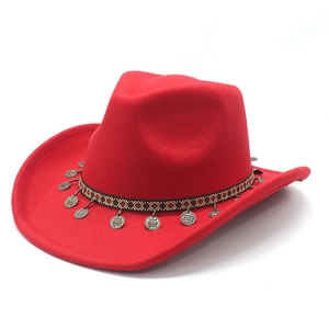 Detail of red cowboy hat with ethnic geometric band and antique metal coin charms