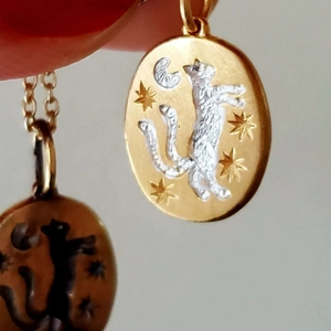 Vue macro du pendentif tarot ovale avec lune, étoiles et chat en bicolore doré et argenté