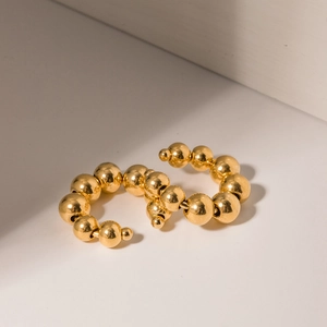 Detail of 18k gold plated stainless steel ear cuff with graduated bead design on white background