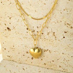 Detailed view of layered gold heart necklace with paperclip chain and horsehoof link design