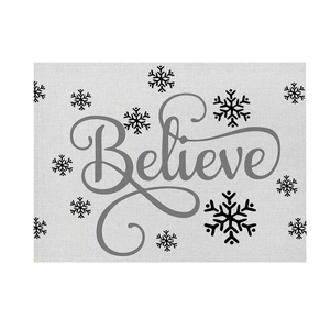Detail of linen texture placemat featuring black snowflake and Believe lettering