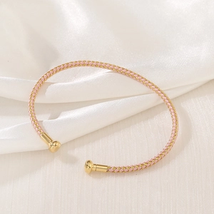 Detail of hand-woven pink and gold silk thread bracelet with metallic spherical ends