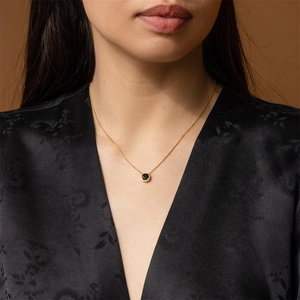 Elegant gold necklace with a black zircon pendant and diamond accents on a female model