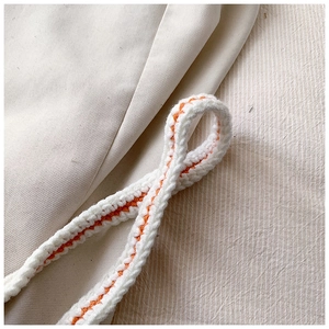 Close-up of white and orange hand-woven shoulder strap with soft cotton texture