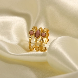 Ring mit rosa ovalen Edelsteinen und mehrlagigem Goldband auf elegantem Seidenhintergrund