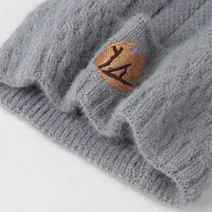 Detailed macro of a grey winter knit beanie featuring plush fabric and embroidered maple leaf patch