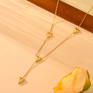 Élégant collier doré à breloques en cœur avec chaîne en Y sur fond floral chaleureux
