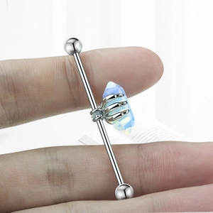 Détail d'un piercing industriel avec pierre bleue tenue par des griffes de dragon argentées