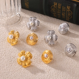 Vintage gold and silver floral earrings with white pearls on a textured stone background