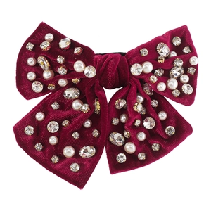Dettaglio del fermaglio per capelli in velluto rosso scuro con perle e strass lucidi