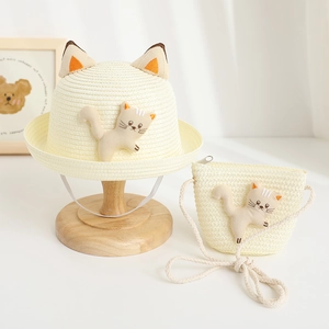 Detail of cream straw hat and matching bag set featuring cute plush cat ears and doll