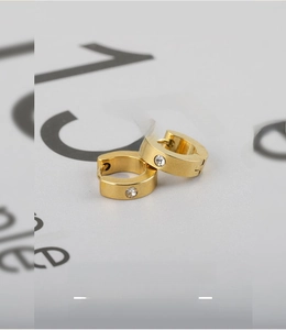 Detail of gold-plated stainless steel huggie earrings with a sparkling round zircon stone