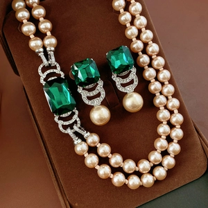 Dettaglio di parure vintage con gemma quadrata color smeraldo e perle champagne