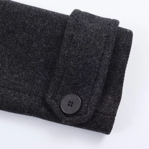 Detail view of charcoal grey wool blend coat sleeve with adjustable cuff and button