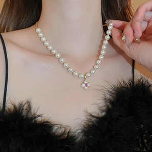 Detail of vintage gold plated pearl necklace with floral pendant and red gemstone