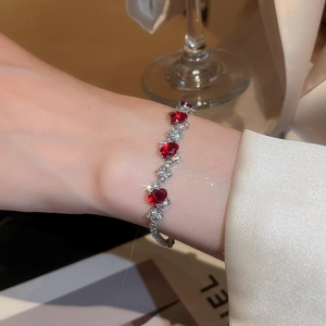 Detail of red gemstone and clear zircon wavy bracelet worn on a female wrist