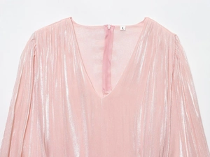 Détail de robe plissée rose à col en V montrant le tissu métallisé et la fermeture éclair