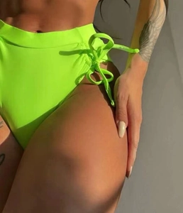 Close-up of neon green high-waisted bikini bottoms with side lace-up cutout details