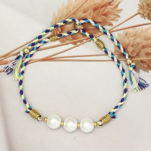 Detailed macro view of multi-color hand-woven rope bracelet with three white glass pearls