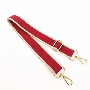 Detail of red geometric fabric bag strap with gold lobster clasps and adjustable buckle