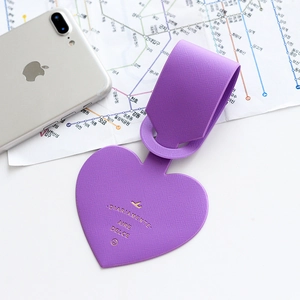 Purple heart-shaped leather luggage tag with gold airplane logo on travel map